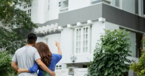 A young couple looking at a two-storey house from the front garden
